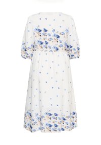 Robe blanche longueur genoux avec motifs floraux bleus et beiges, manches bouffantes et taille élastique.