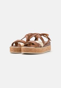 Sandali platform in pelle marrone con suola in sughero, design a fasce incrociate e una singola fascia regolabile alla caviglia. Finitura texture.