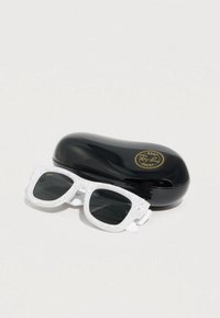 Γυαλιά ηλίου με λευκό πλαίσιο και μαύρους φακούς στολισμένους με στρας δίπλα σε μαύρη θήκη Ray-Ban με χρυσό λογότυπο ASAP Rocky.