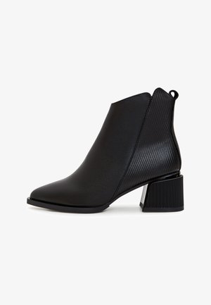 Stivaletto nero alla caviglia con punta affilata, superiore in sintetico liscio, dettaglio rigato sul tacco e tacco a blocco con finitura lucida nera e argento.