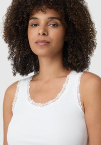 Biała ribbed top bez rękawów z koronkowym wykończeniem wokół dekoltu i ramiączek. Gładka faktura i dopasowany krój.