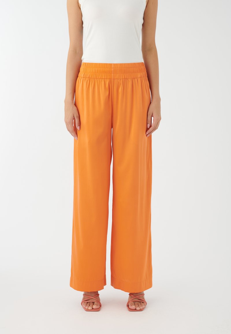 Pantalons à taille haute et jambe large en tissu orange vif avec une texture lisse. Dotés d'une taille élastique pour le confort.