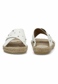 Bílé espadrilky s kříženými popruhy, dekorativními rhinestonemi a juty obalenou podrážkou na plochém gumovém základu.