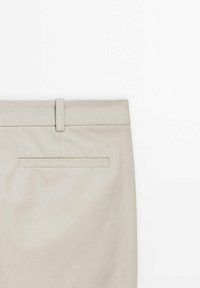 Beiga byxor med en slät yta, som har en smal midja och en bakficka med en ren, sydd kant.