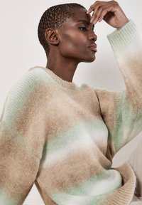 Beiger und mintgrüner gestreifter Pullover aus weichem, strukturiertem Stoff mit Rundhalsausschnitt und lockerer Passform, der ein Farbverlaufsmuster zeigt.
