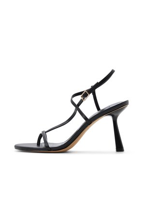 Czarna sandałka na wysokim obcasie z cienkimi paskami, zapięciem na klamrę i rozszerzanym obcasem na białym tle.