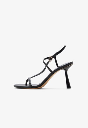 Sort højhælet sandal med tynde remme, spænde og en udvidet hæl på hvid baggrund.