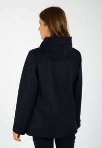 Marinblå huva jacka i mjukt material, med avslappnad passform, sidofickor och en enkel design med sydda detaljer på huvan.