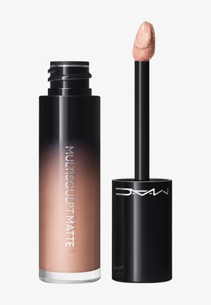 Flacon de correcteur liquide mat avec un applicateur en forme de patte de daim, le produit est d'une teinte beige clair avec des bouchons noirs brillants.