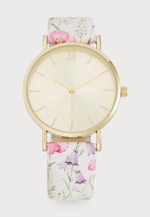 Montre à bordure dorée avec cadran crème, marqueurs d'heure dorés minimalistes, et bracelet en tissu à motif floral avec des fleurs roses et violettes.