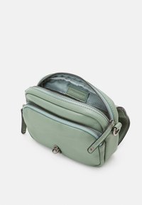 Bolso bandolera de cuero verde suave con dos compartimentos con cremallera, parcialmente abierto mostrando el forro de tela claro con etiqueta de la marca en el interior.