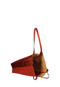 Metalen oranje schoudertas met een zachte bruine binnenkant, voorzien van twee lange hengsels en een open bovenkant. Eenvoudig ontwerp zonder extra patronen.