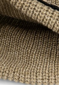 Close-up of a folded brown knitted fabric showing detailed ribbed texture and thick yarn fibers.