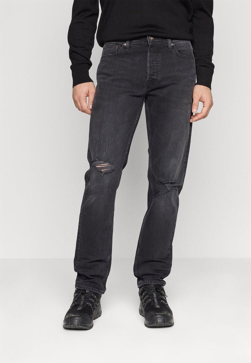 Svarta jeans av denim med slim fit, femfickorsdesign, lätt slitage vid knäna och kontrasterande sömmar. Tillsammans med mörka skor.
