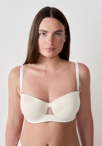 Reggiseno beige chiaro con ferretto, coppe imbottite senza cuciture, pannello in rete al centro, spalline in satin regolabili, texture liscia, design minimalista.