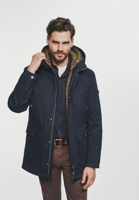 Granatowa parka z brązowym podszewką, posiadająca kaptur, zamek błyskawiczny z przodu oraz napy. Teksturowana tkanina z dwoma przednimi kieszeniami.