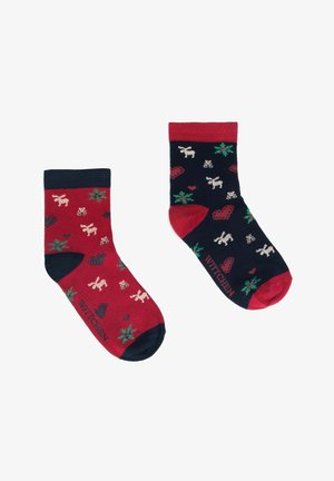 Chaussettes rouges et navy avec divers motifs incluant des rennes, des cœurs et des feuilles ; fabriquées à partir d'un textile doux. Logo imprimé sur l'avant inférieur.