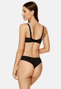 Czarny biustonosz typu bralette i pasujące stringi, z regulowanymi ramiączkami, gładką teksturą oraz minimalistycznym wzornictwem bez widocznych wzorów czy akcentów.