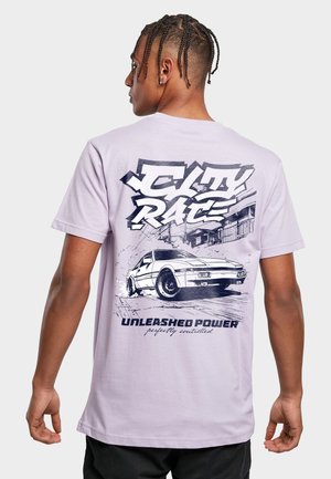 Ung mann med fletter iført en lys lilla t-skjorte med en hvit sportsbil og grafikk med teksten "City Race Unleashed Power" på baksiden.