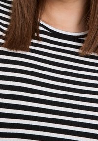 Černobíle pruhovaná tkanina s žebrovanou texturou a kulatým výstřihem, s rovnoměrnými horizontálními pruhy a hladkými švy.