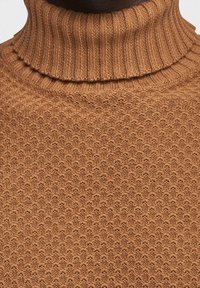 Pull à col roulé en tricot marron avec un motif texturé et un col côtelé, présentant une vue rapprochée de ses détails tissés et de sa couleur.