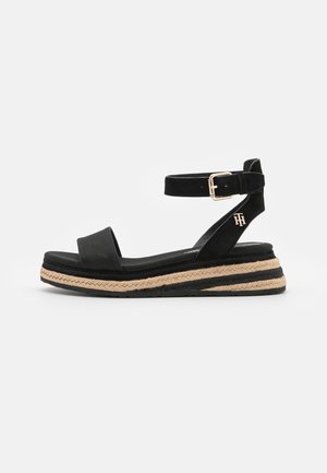 Sorte wedge-sandaler i ruskind med bred rem over foden, ankelrem med spænde og en platform pakket ind i jute med sorte striber.