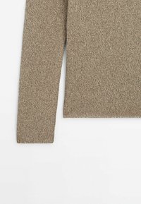 Pull tricoté à manches longues beige avec un motif de points simple et texturé, présenté à plat sur fond blanc.