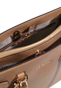 Brun syntetisk håndtaske med gylden lynlås, med en tekstureret yderside, to rum og et mønstret inderfor.