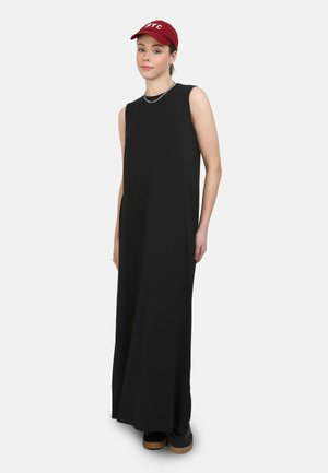 Abito maxi nero senza maniche con una vestibilità ampia, realizzato in tessuto morbido. Abbinato a un cappellino da baseball bordeaux e scarpe nere con tacco in legno.