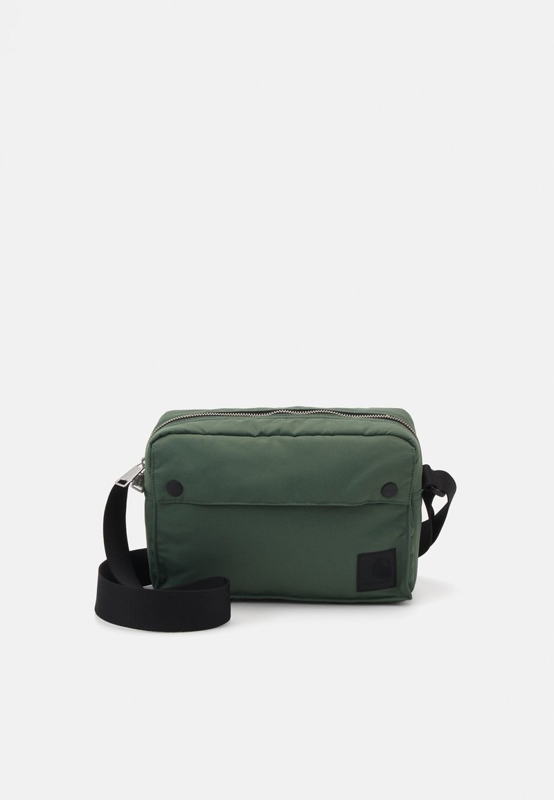 Grøn rektangulær crossbody taske med frontlomme med klap, sort justerbar rem og sølv lynlås på hvid baggrund.