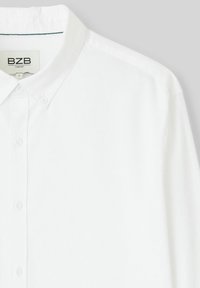 Chemise blanche à manches longues avec col classique, patte de boutonnage intégrale et texture subtile. Étiquette BZB visible à l'intérieur du col.