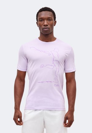 Homme portant un t-shirt violet clair avec un croquis violet d'un joueur de tennis en train de balancer une raquette, assorti à un short blanc sur un fond uni.
