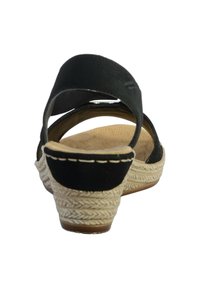 Sandali neri con tacco in juta intrecciata e soletta color cuoio, dotati di due fasce incrociate per una vestibilità sicura. Superficie liscia nella parte superiore.