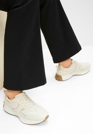 Sneaker atletici beige realizzati in tela e gomma, con suola testurizzata e design con lacci, caratterizzati da un delicato dettaglio di branding.