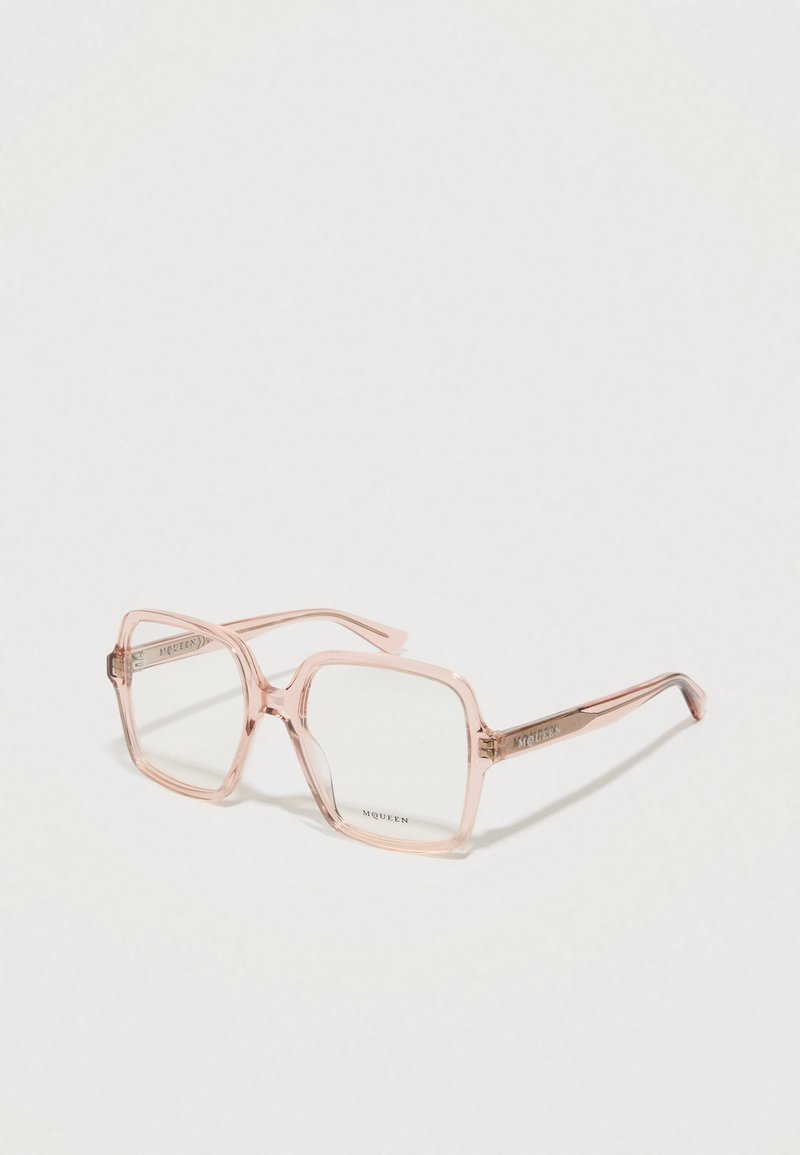 Óculos quadrados com armação transparente cor-de-rosa, lentes transparentes e acabamentos metálicos, apresentando o nome da marca "McQueen" nas hastes.