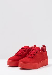 Baskets plateforme en daim rouge avec semelles en caoutchouc texturé, bouts ronds et lacets assortis. Équipées d'une languette à l'arrière pour un enfiler facile.