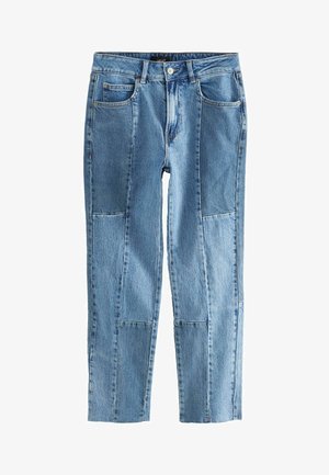 Sininen farkkutakki, jossa on suora lahje, useita taskuja ja haalistunut pesu, jossa on näkyvät saumat ja paikkaustyöt.