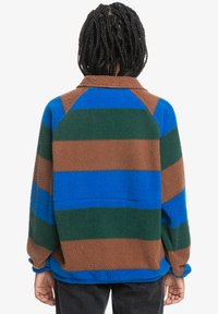 Pull en polaire avec des rayures horizontales marron, vert et bleu. Présente un col et une coupe décontractée. Tissu texturé et chaud.