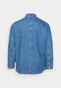 Džínová bunda v světle modré barvě s rovný střihem, dlouhými rukávy, knoflíkovými manžetami a límcem. Žádné přední kapsy nejsou viditelné.