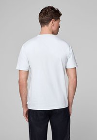 Jasnoniebieska bawełniana koszulka z krótkimi rękawami, okrągłym dekoltem i gładkim tyłem. Tkanina wydaje się miękka i gładka.