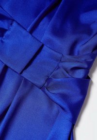 Robe bleu royal en satin lisse, avec une large ceinture à la taille et un tissu superposé et fluide avec des plis diagonaux.