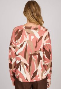 Pull en tricot avec un motif de feuilles multicolores dans des tons de rose, crème et marron, avec un col rond et un ourlet côtelé.