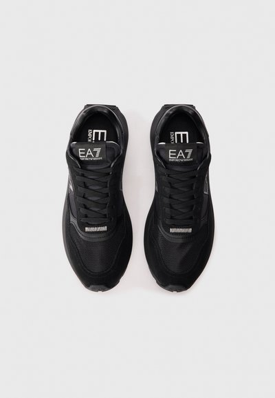 Baskets de sport noires avec une tige en maille et des accents en daim. Présentent des lacets, un logo sur la languette et une semelle en caoutchouc texturée.