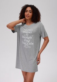 Nightgown grigio in cotone con maniche corte, una vestibilità comoda e grafiche bianche che recitano: "Dai Sogni alla Luce del Giorno Trova la Tua Calma".