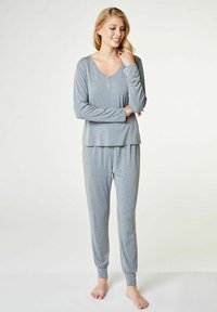 Grå, långärmad pyjamas i mjukt tyg. Har en henley-krage och avslappnade byxor med elastiska muddar vid anklarna.