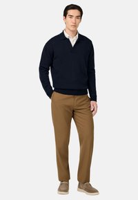 Námornícky pletený pulóver s golierom, skombinovaný s béžovými nohavicami a taupe teniskami. Hladká textúra, voľný strih a jednoduché dizajnové detaily.