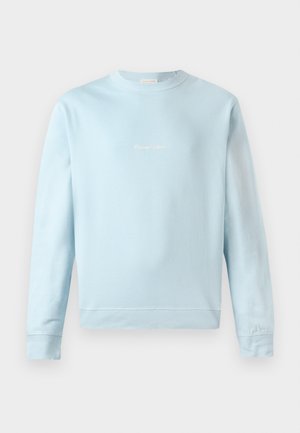 Lys blå sweatshirt laget av myk bomull, med rund hals, ribbede mansjetter og en liten, subtil logo sydd på forsiden.