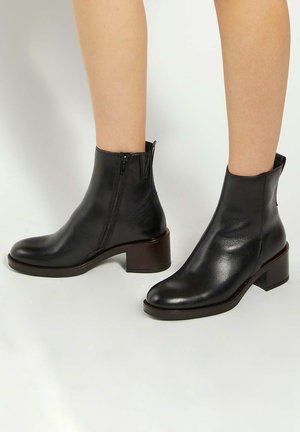Black leather ankle boots with a rounded toe, side zipper, and a block heel. Smooth texture with minimal accents.