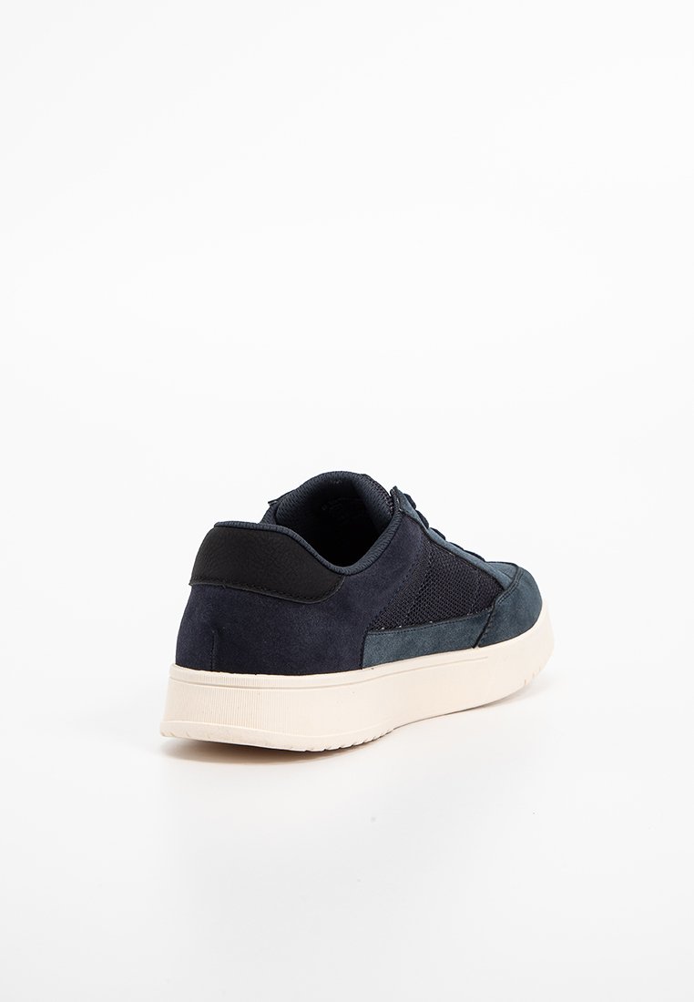 Sneaker blu navy con tomaia in suede e mesh, punta rotonda e suola in gomma bianca. Presenta un colletto imbottito e cuciture tonali.