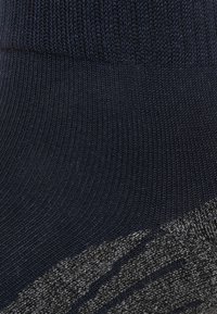 Calcetín azul marino con textura de canalé en la parte superior y un acento gris con patrón en la parte inferior, que presenta rayas diagonales y un acabado suave.